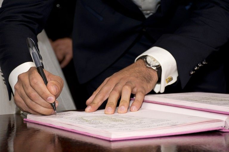 Image représentant des associés signant un contrat de société pour une société d'attribution.